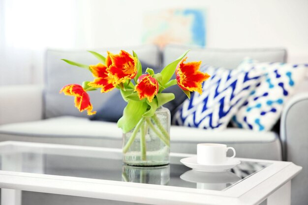 Un ramo de tulipanes rojos en un vaso sobre una mesa blanca