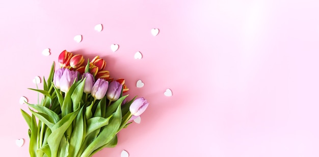 Ramo de tulipanes rosados con chispitas de corazón decorativo sobre fondo claro pastel suave. Vista superior. Fondo festivo del día de San Valentín.