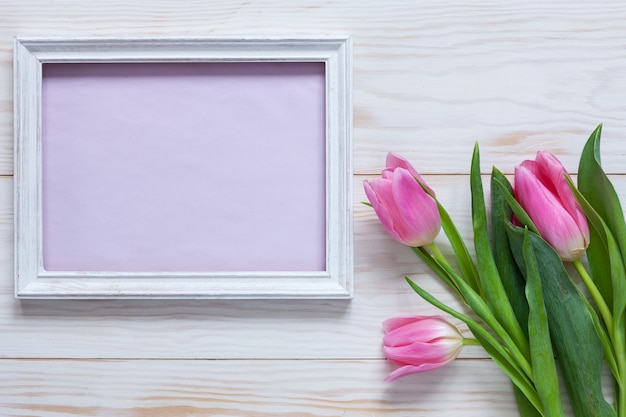 Ramo de tulipanes rosados y lugar para texto en marco de madera blanco