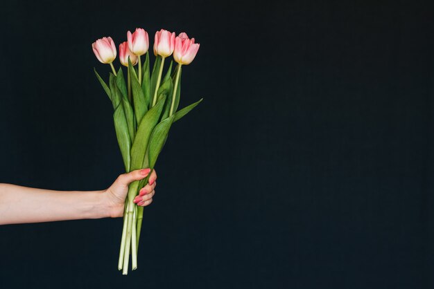 Ramo de tulipanes rosados en mano de mujer