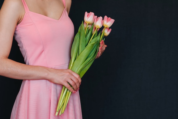 Ramo de tulipanes rosados en manos de mujer