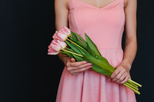 Ramo de tulipanes rosados en manos de mujeres