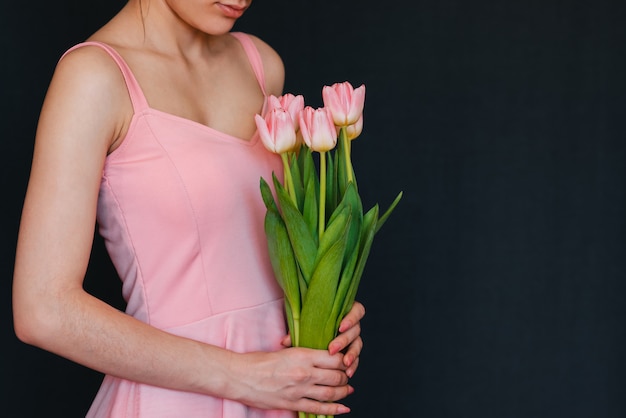 Ramo de tulipanes rosados en manos de mujeres