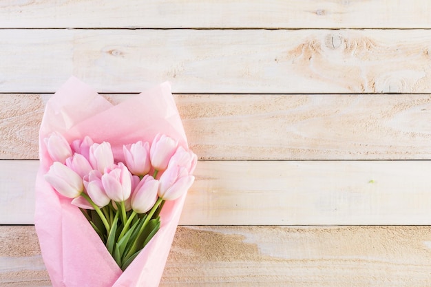 Ramo de tulipanes rosas envuelto en papel rosa.