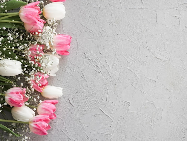 Ramo de tulipanes rosas y flores blancas de gypsophila sobre un elegante fondo de piedra gris Concepto de celebración de cumpleaños del Día de la Madre Copiar espacio para texto Mockup