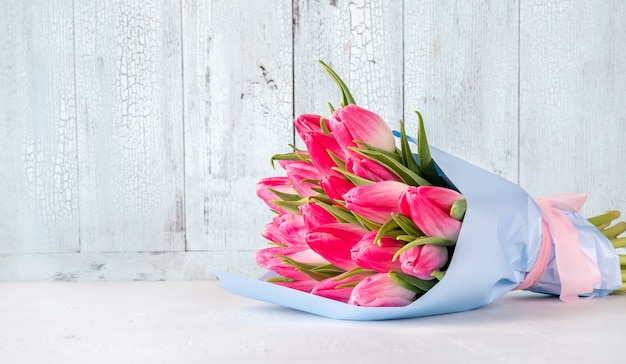 Ramo de tulipanes rosas en la mesa de madera