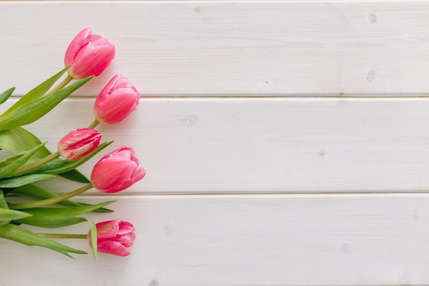 Ramo de tulipanes rosas sobre fondo blanco de madera Vista superior copia espacio