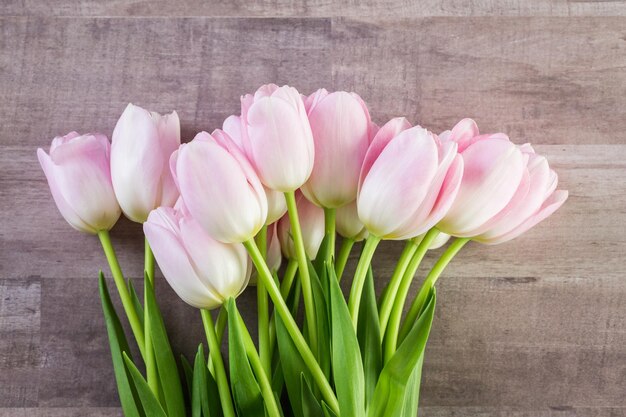Ramo de tulipanes rosas sobre un fondo de madera.