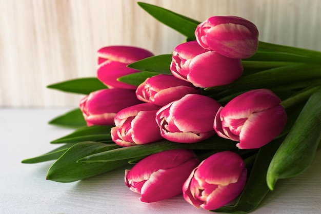 Ramo de tulipanes rosas sobre fondo de mesa blanca en mal estado para el saludo navideño