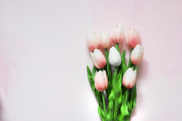 Ramo de tulipanes rosas sobre un fondo pintado de madera clara