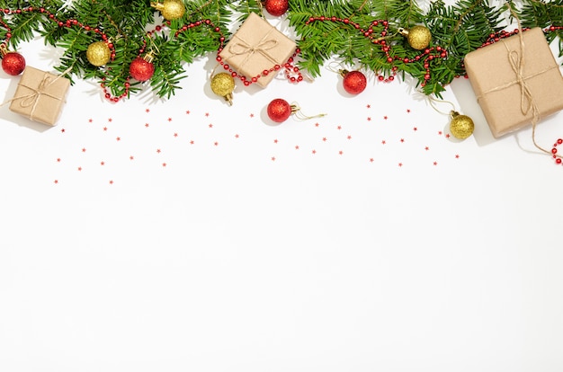 Ramos de abeto, caixas de presente, bolas de Natal de cor vermelha e dourada para decoração, miçangas vermelhas para decoração em um fundo branco. Copie o espaço, plana lay. Vista de cima