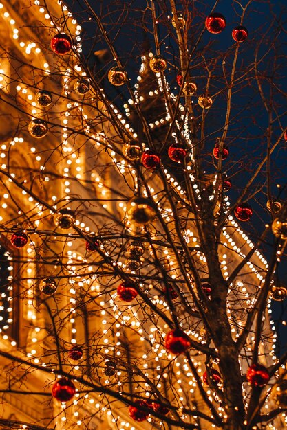 Foto ramos de árvores de construção dourados decorados com bolas de natal em uma atmosfera de noite festiva