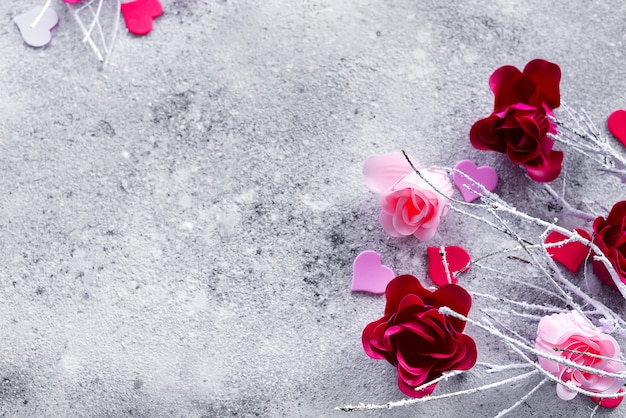 Ramos na neve com rosa e botões de rosa vermelhos e corações em um fundo de concreto