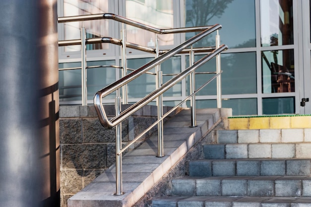 Una rampa y barandillas metálicas en la entrada del edificio residencial para comodidad de las personas con discapacidad y de la tercera edad