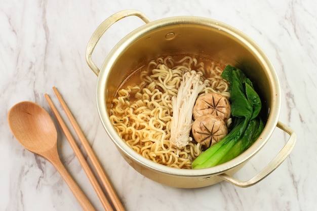 Ramyeon coreano em panela de ouro, sirva com cogumelo enoki e vegetais. servido strait em uma panela para manter aquecido. copiar espaço para texto