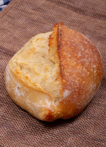 Randansicht eines Brotlaibs mit rötlicher Kruste auf Sackleinenhintergrund