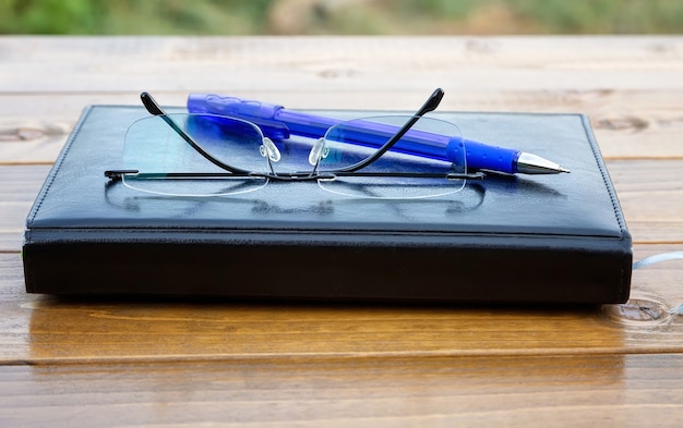 Foto randloses brillen-stift-notizbuch auf einem holztisch-nahaufnahme