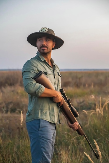 ranger de chapéu fica em um campo com uma arma