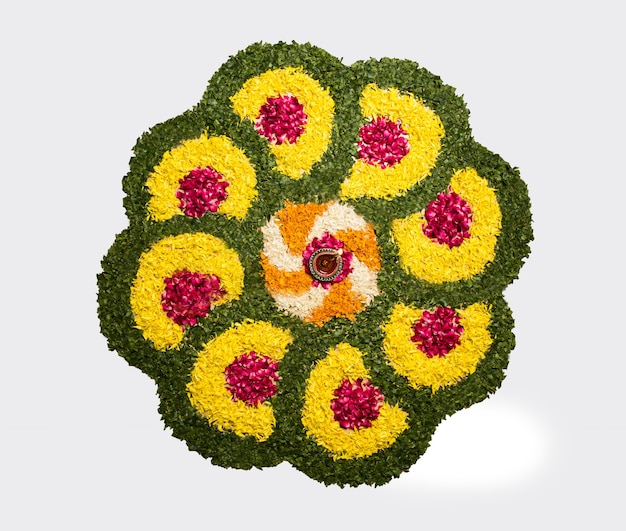 Rangoli de flores para Diwali ou Pongal feito com flores de calêndula ou zendu e pétalas de rosa vermelha sobre fundo branco com lâmpada de óleo de argila no meio, foco seletivo