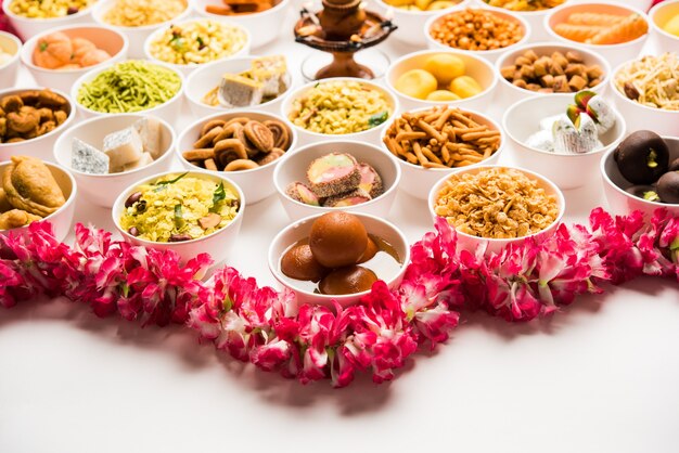 Foto rangoli von süßigkeiten und farsan oder snacks in schalen für diwali mit diya auf weißem hintergrund