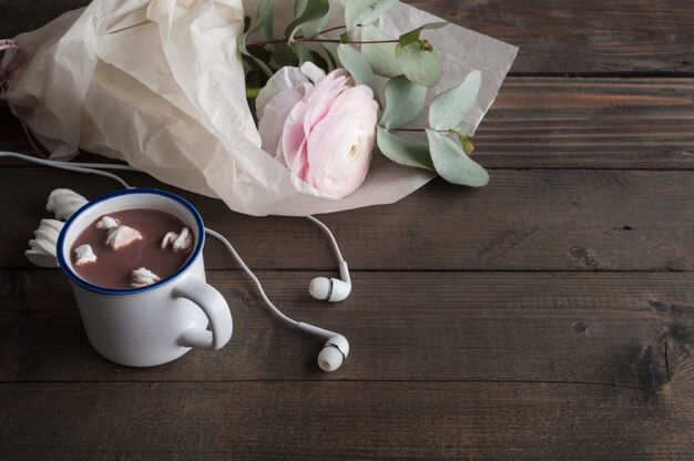 Ranúnculo rosa, fones de ouvido e chocolate quente