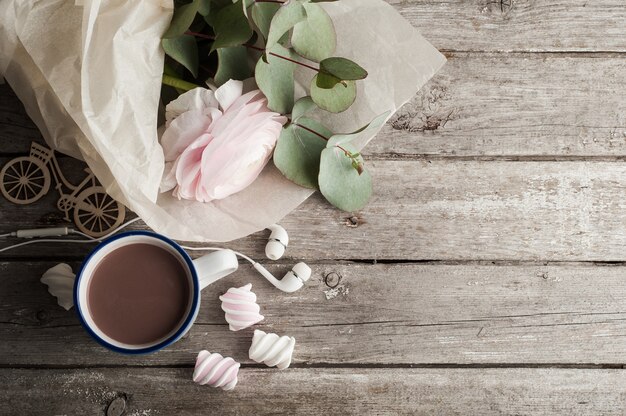 Ranúnculo rosado, auriculares, chocolate caliente