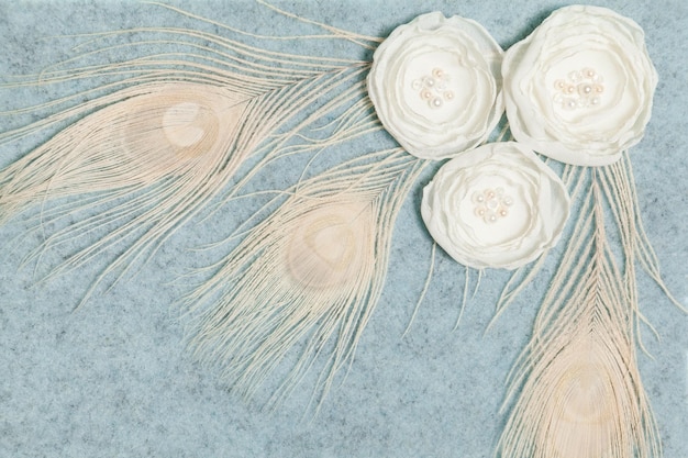 Ranunculus blanco suave hecho a mano flores plumas de pavo real, fondo de lana gris vista plana superior