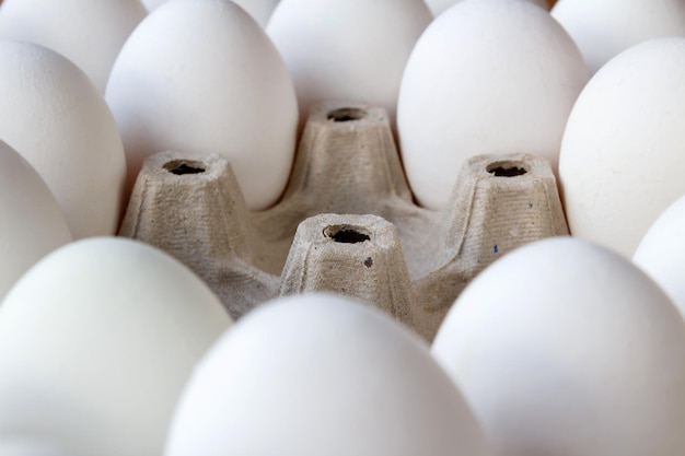 Ranura vacía en bandeja de cartón entre huevos blancos closeup