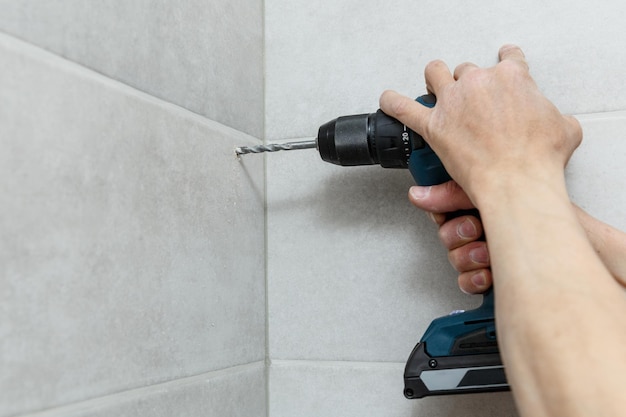 Rapairman perforando baldosas de cerámica en una pared.