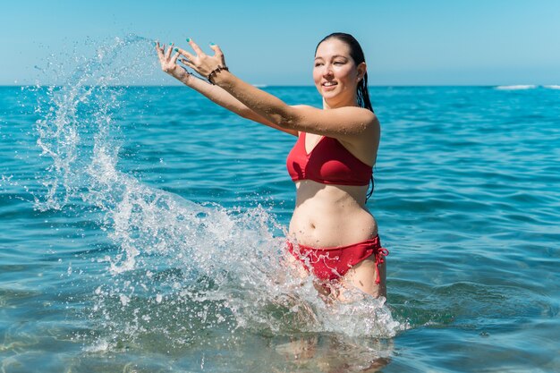 Rapariga a divertir-se a tomar banho no mar e a espirrar água