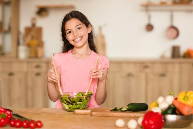 Rapariga a fazer salada na cozinha ensolarada