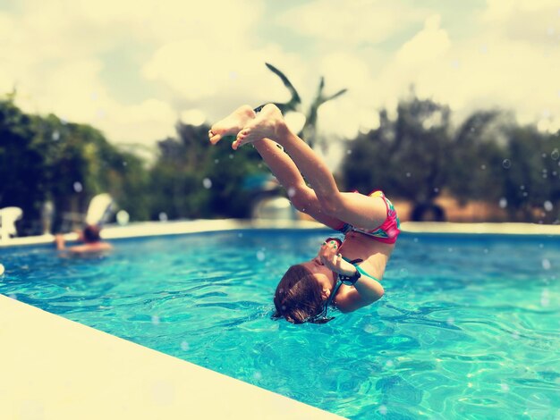 Foto rapariga a saltar na piscina