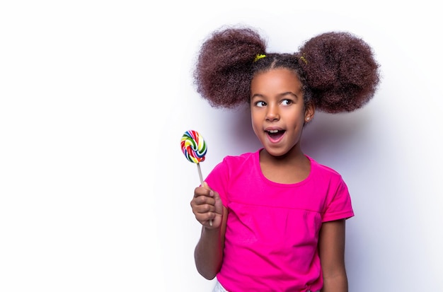 Rapariga afro pirulito Sorrindo pequena garota americana comendo pirulito segurando rosa doce
