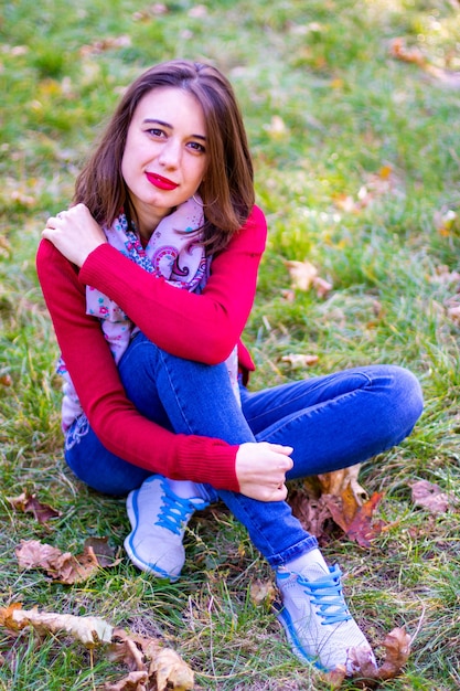 Rapariga com camisola vermelha na natureza. Menina de vermelho na natureza. Menina com lábios vermelhos. Foto de outono