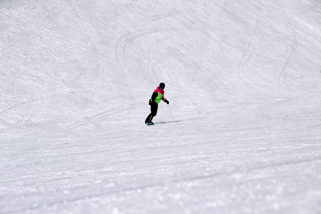 Rapariga com um fato colorido a andar de snowboard numa montanha