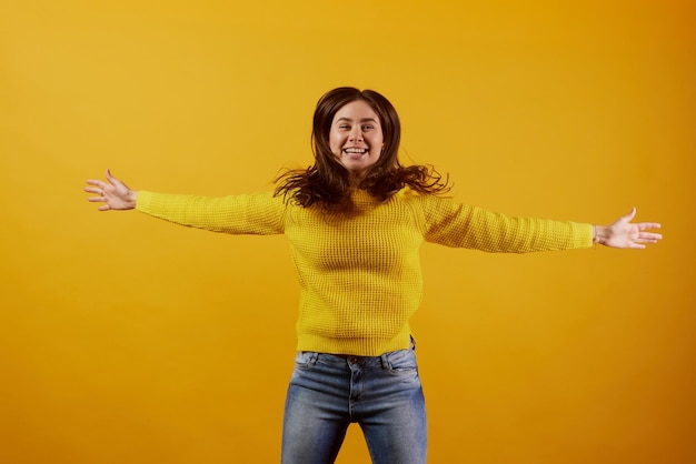 rapariga de suéter amarelo alegra-se com um fundo amarelo