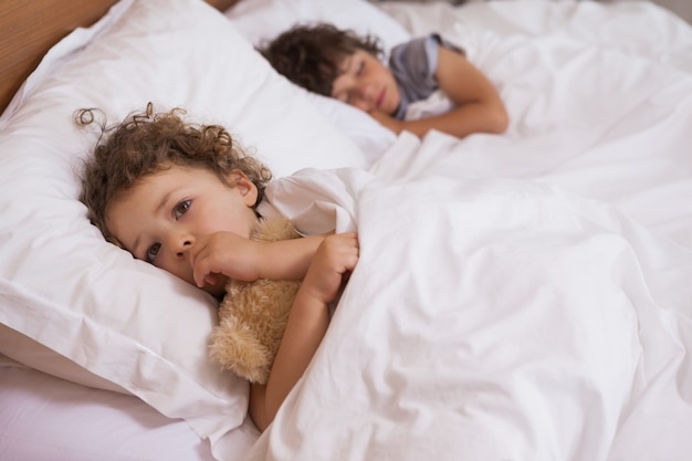 Rapariga e menino dormindo na cama