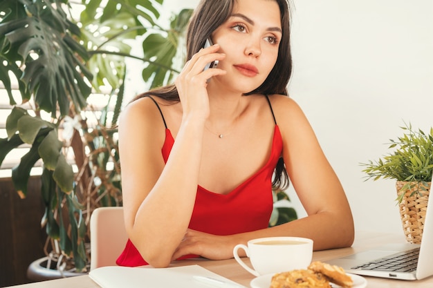 Rapariga estudante falando ao telefone enquanto está sentado no café