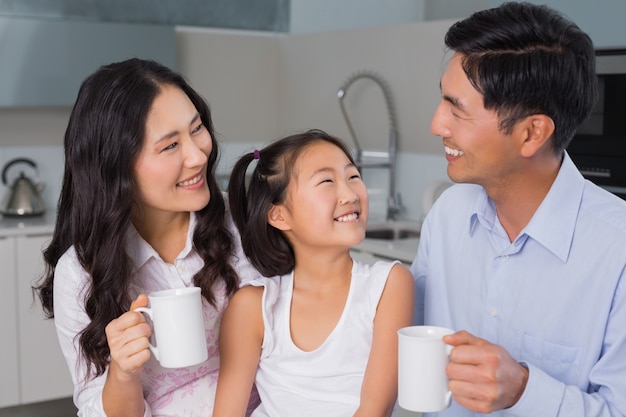 Rapariga feliz, desfrutando de café da manhã com os pais