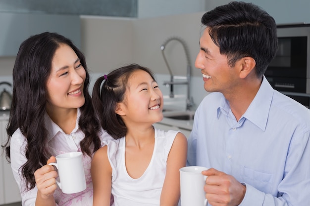 Rapariga feliz, desfrutando de café da manhã com os pais