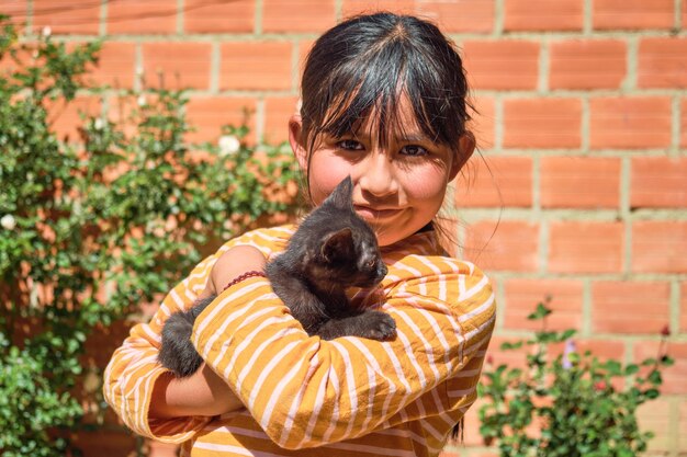 Foto rapariga latina boliviana agarrando um pequeno gato ao ar livre