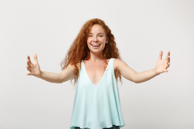 Rapariga ruiva sorridente jovem em roupas leves casuais posando isolado no fundo da parede branca. Conceito de estilo de vida de pessoas. Simule o espaço da cópia. Gesticulando demonstrando tamanho com espaço de trabalho horizontal.