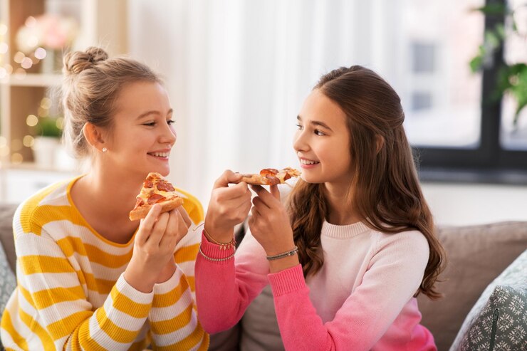 Foto raparigas adolescentes felizes a comer pizza em casa