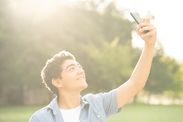 Rapaz adolescente hispânico tomando selfie ao pôr do sol