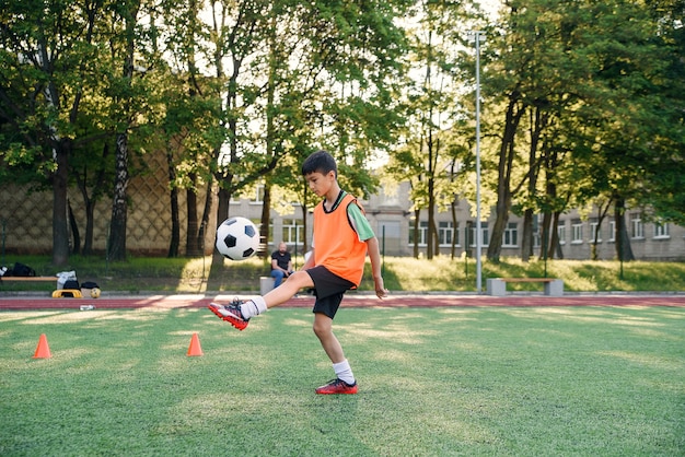 Rapaz adolescente jogando futebol no campo de futebol