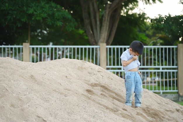 Rapaz asiático brincando com areia e brinquedo em parque público