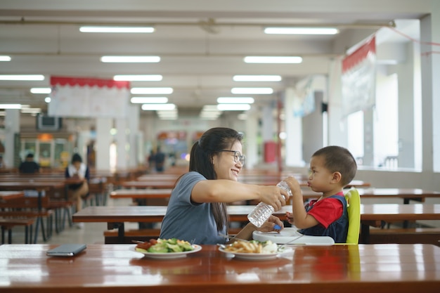 Rapaz asiático comendo comida alimentada por sua mãe