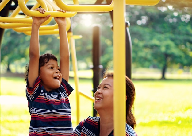 Rapaz asiático e mães asiáticas estão brincando no playground, divertido e sorrindo.