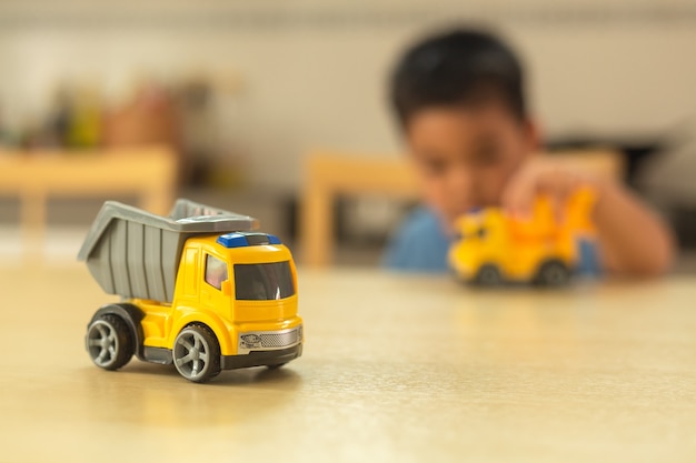 Foto rapaz asiático está brincando com carros de brinquedo em casa