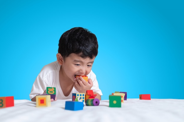 Rapaz asiático jogar brinquedo de quebra-cabeça de bloco quadrado na cama